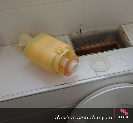 מיכל פלסטיק צהוב על אסלה בחדר אמבטיה